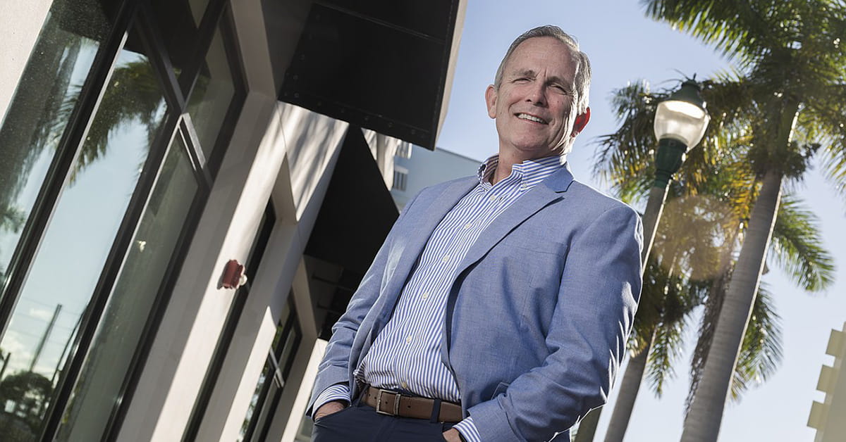 Ed Jahn in blazer standing outside modern building with palm trees