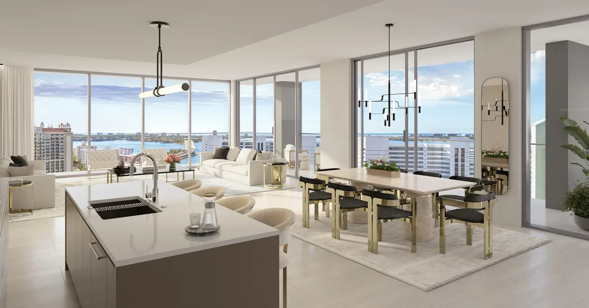 Luxury high-rise open-concept living space featuring a sleek kitchen island, gold-accented dining set, and floor-to-ceiling windows with panoramic waterfront...