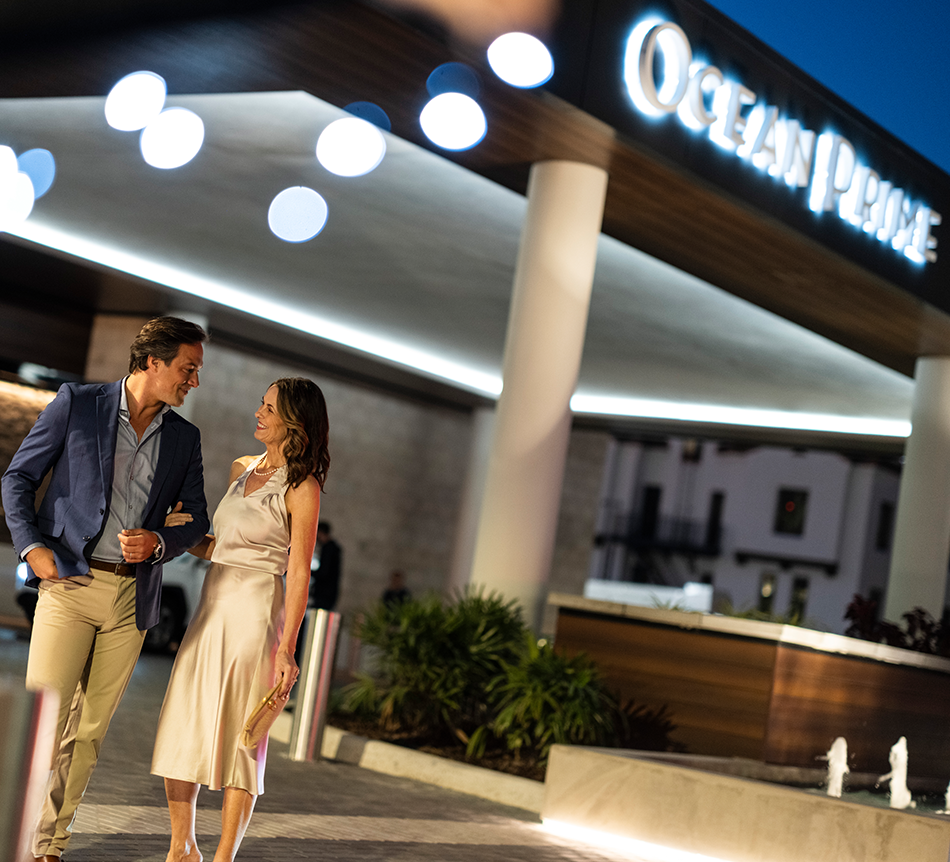 Dining lifestyle image for 1000 Boulevard of the Arts, showing a couple arriving at Ocean Prime in downtown Sarasota. Ocean Prime is part of the acclaimed restaurant scene near The Quay, supporting a walkable dining lifestyle from 1000 Boulevard of the Arts.